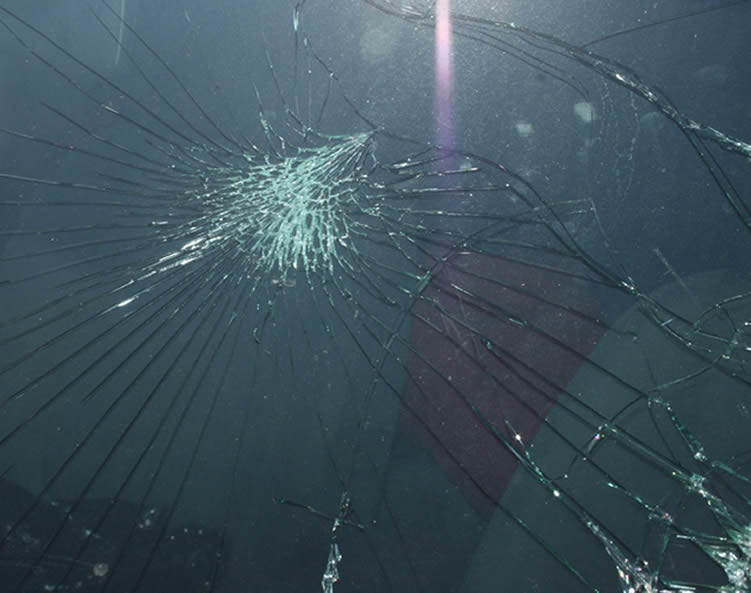 A windshield obviously shattered with cracks radiating from an impact point