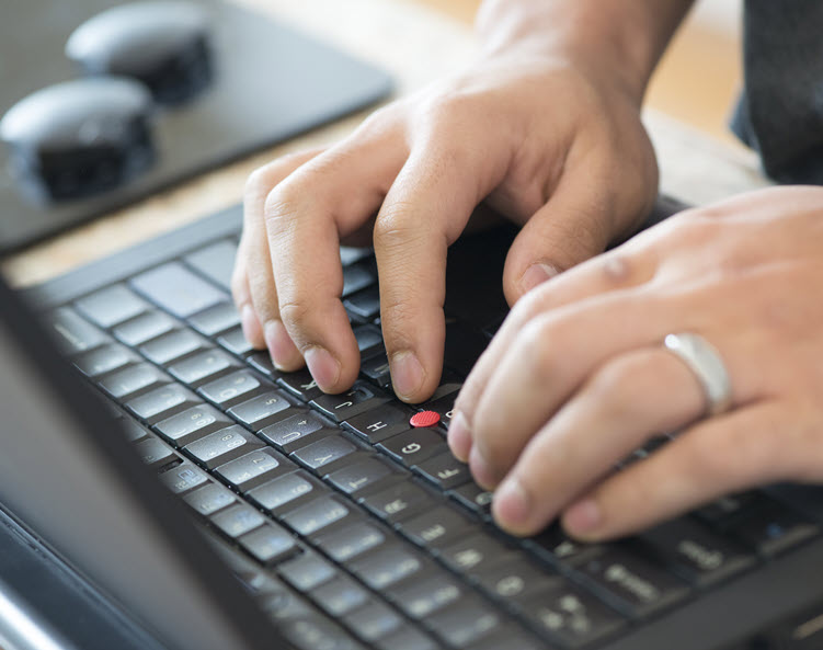 A pair of hands type on a laptop keyboard